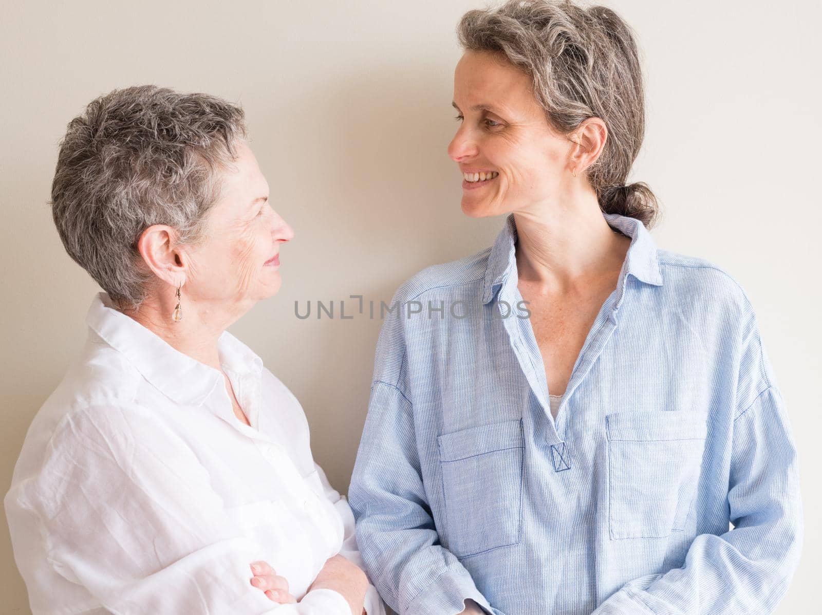 Middle aged daughter and older mother smiling at each other by natalie_board