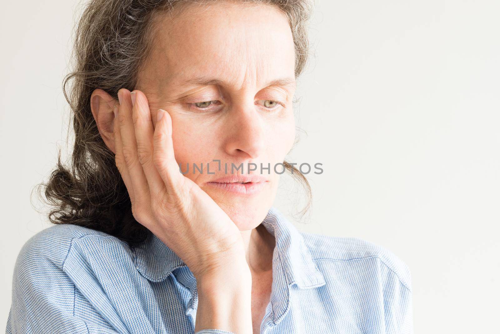 Close up of middle aged woman with hand on face by natalie_board