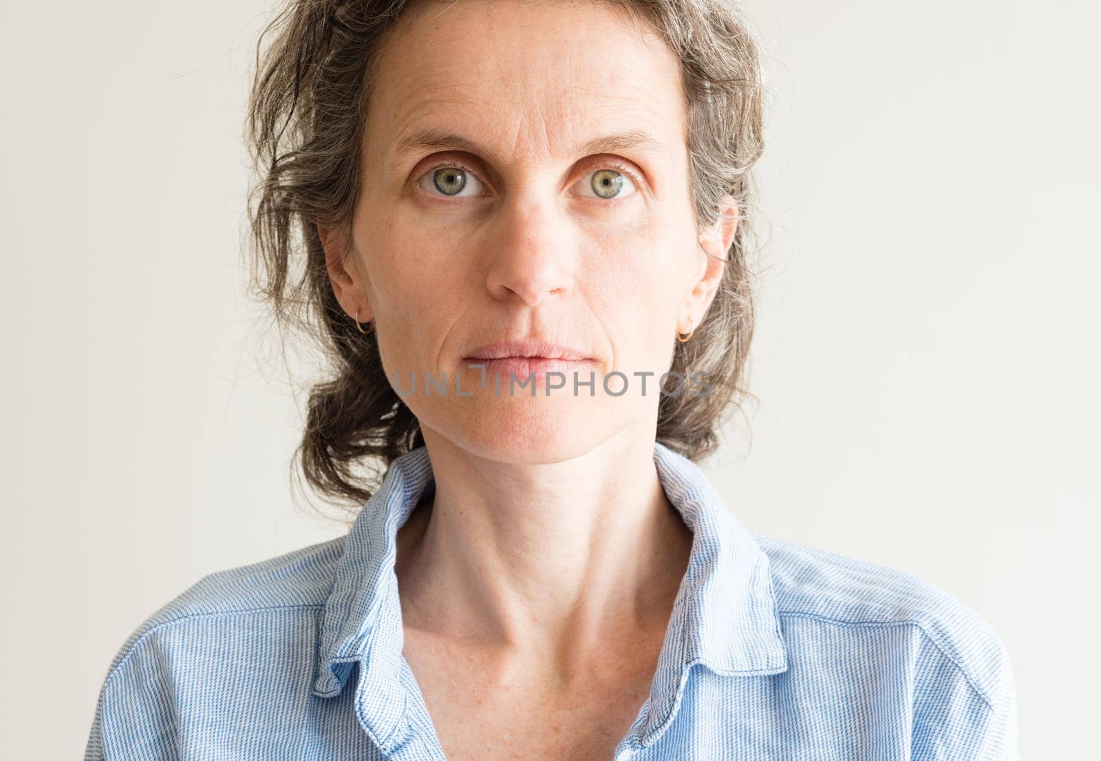 Portrait of natural looking middle aged woman with grey hair in blue shirt