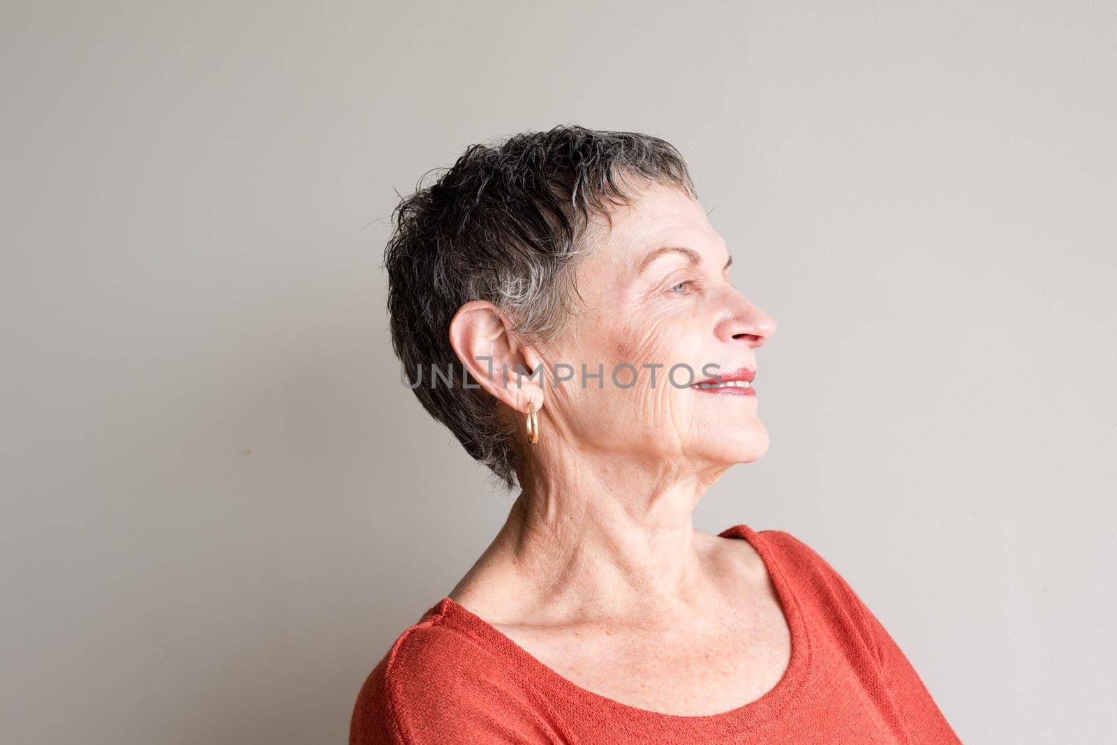 Older woman with short grey hair and orange top smiling with head back by natalie_board