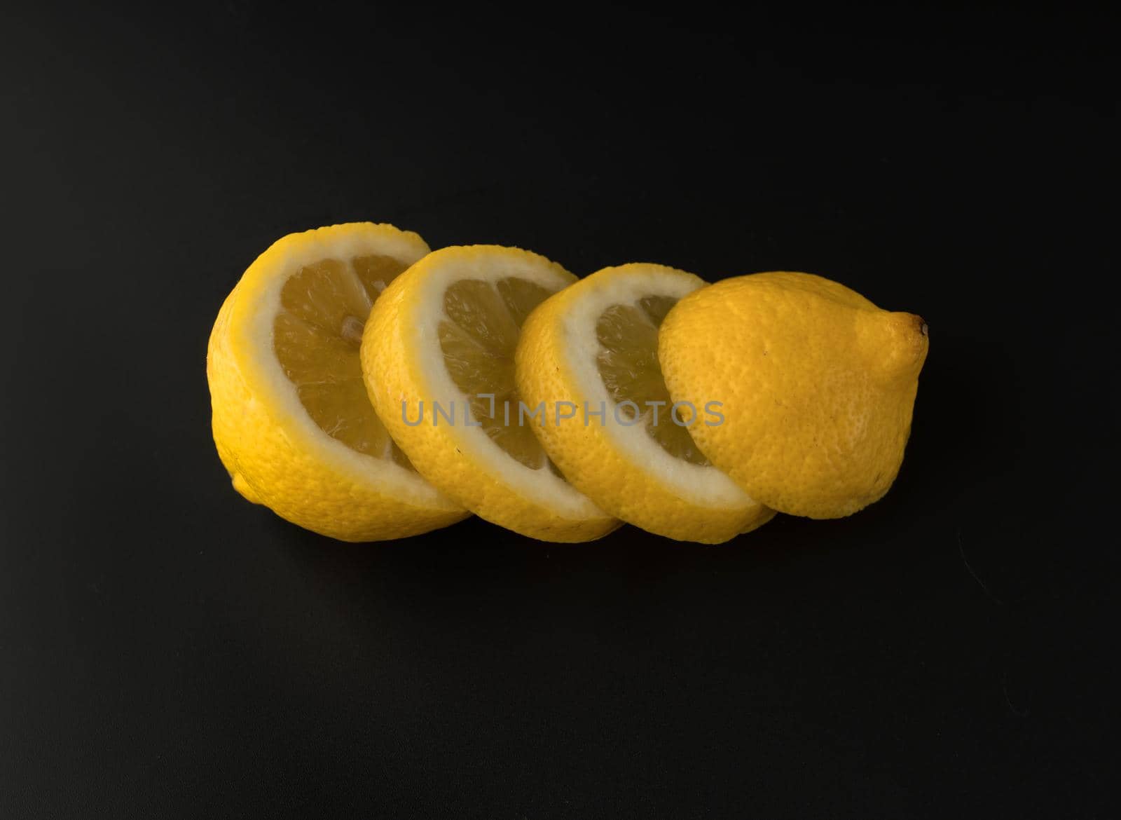 Lemon sliced in round slices, on black background isolated