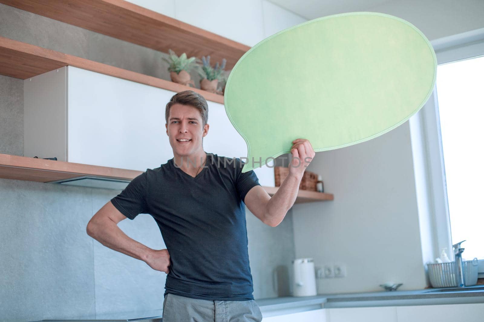 smiling man with a balloon for text standing in the new kitchen. photo with copy space