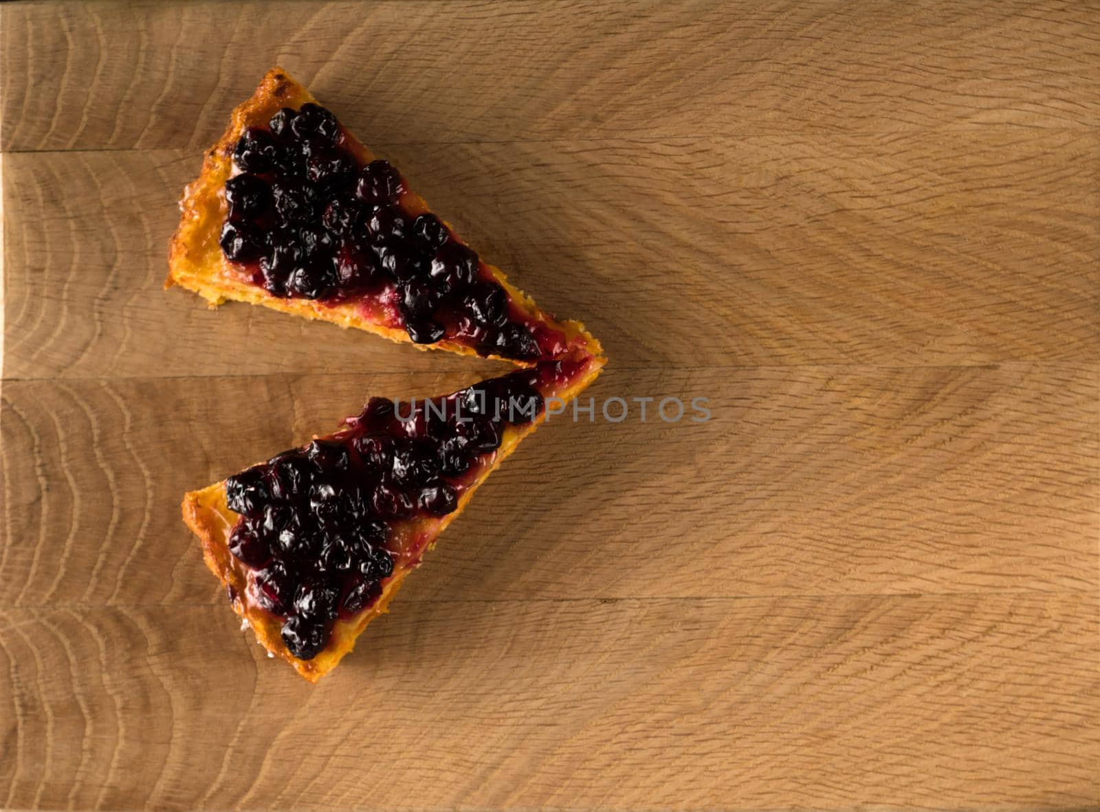 Two slices of carrot cake, thickly covered with currant berries on top, charlotte, on a wooden board