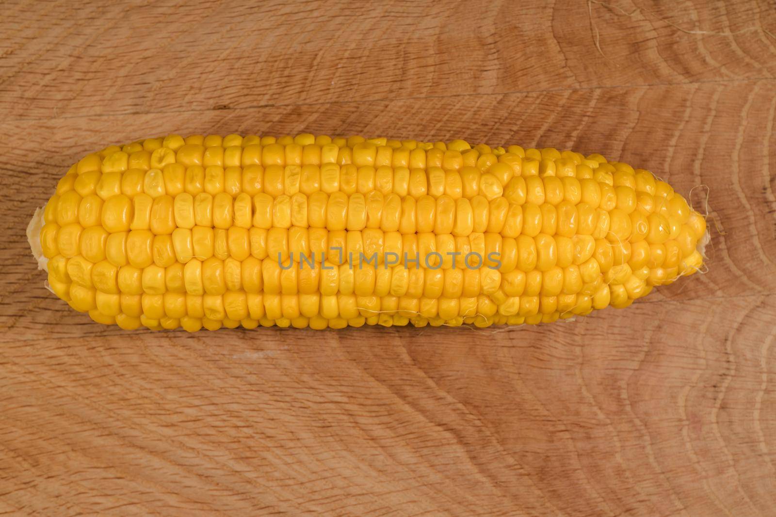 Ripe corn in a roach peeled from husk on a wooden board