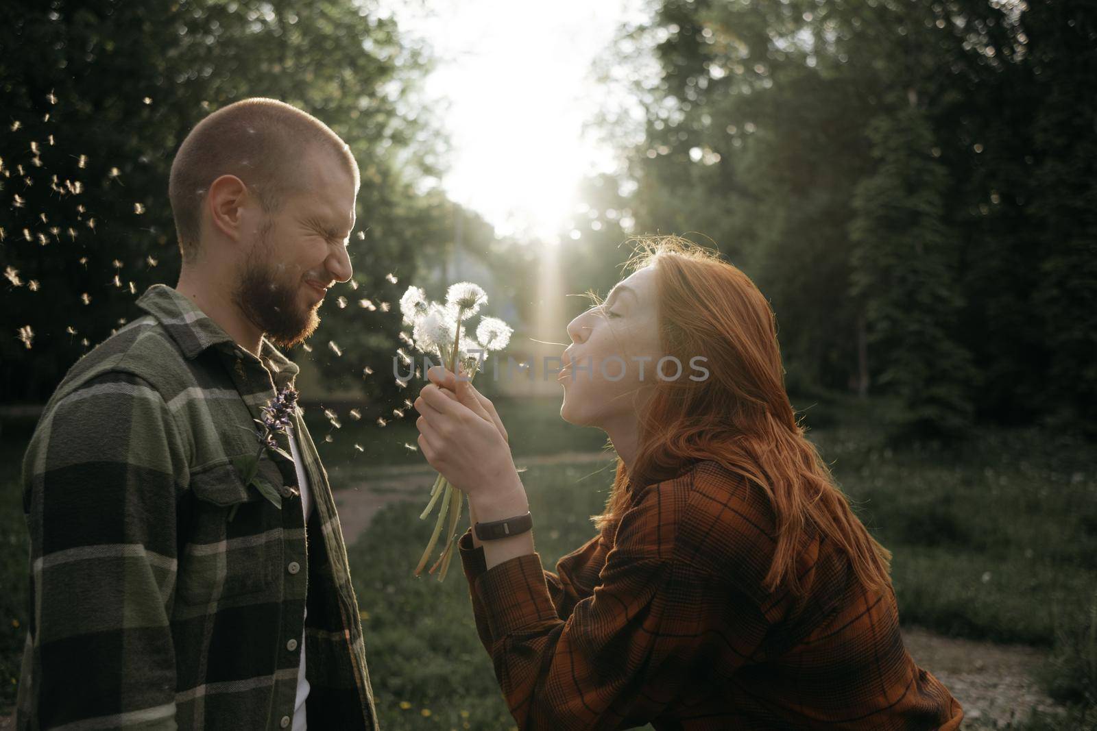 red girl blows a dandelion on her boyfriend by Symonenko