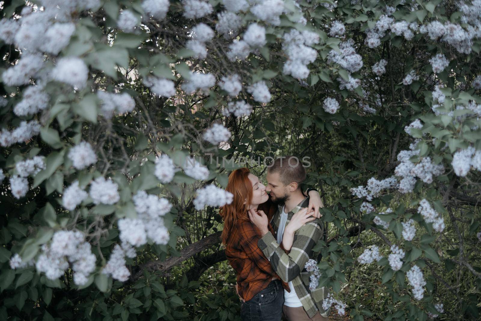 lovers embrace standing under lilacs by Symonenko