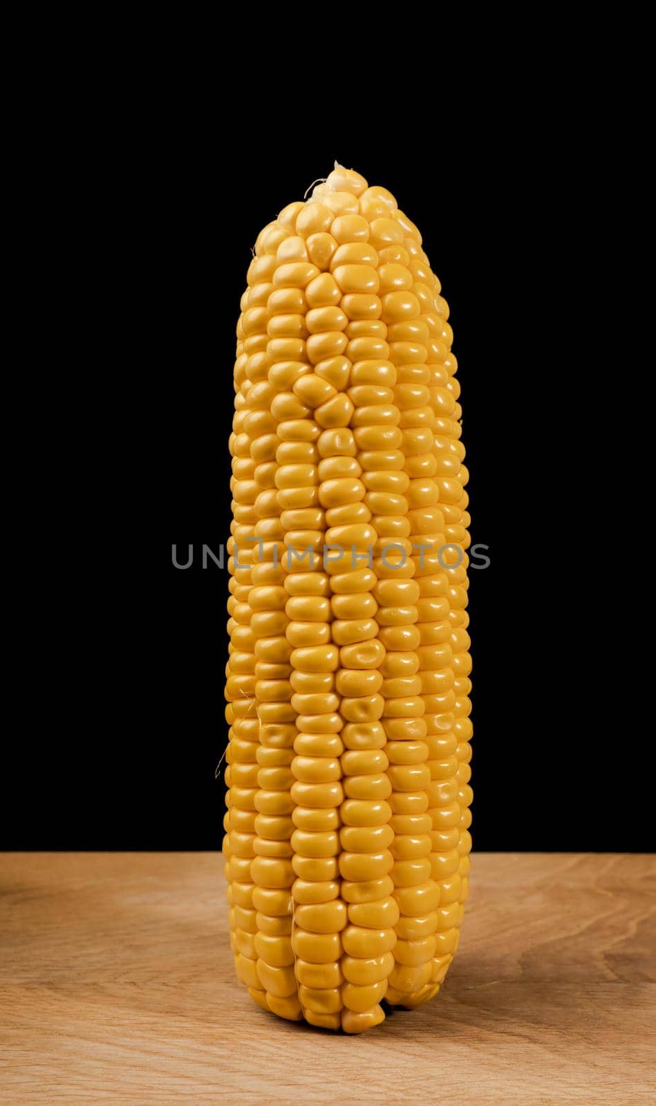 Ripe corn in a head of cabbage half peeled, on a wooden board and a black background