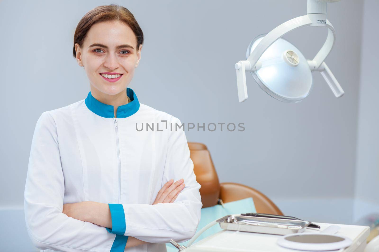 Portrait of a happy beautiful female dentist posing proudly at her dental clinic, copy space. Cheerful dentist in uniform smiling confidently to the camera with her arms crossed. Medicine, health