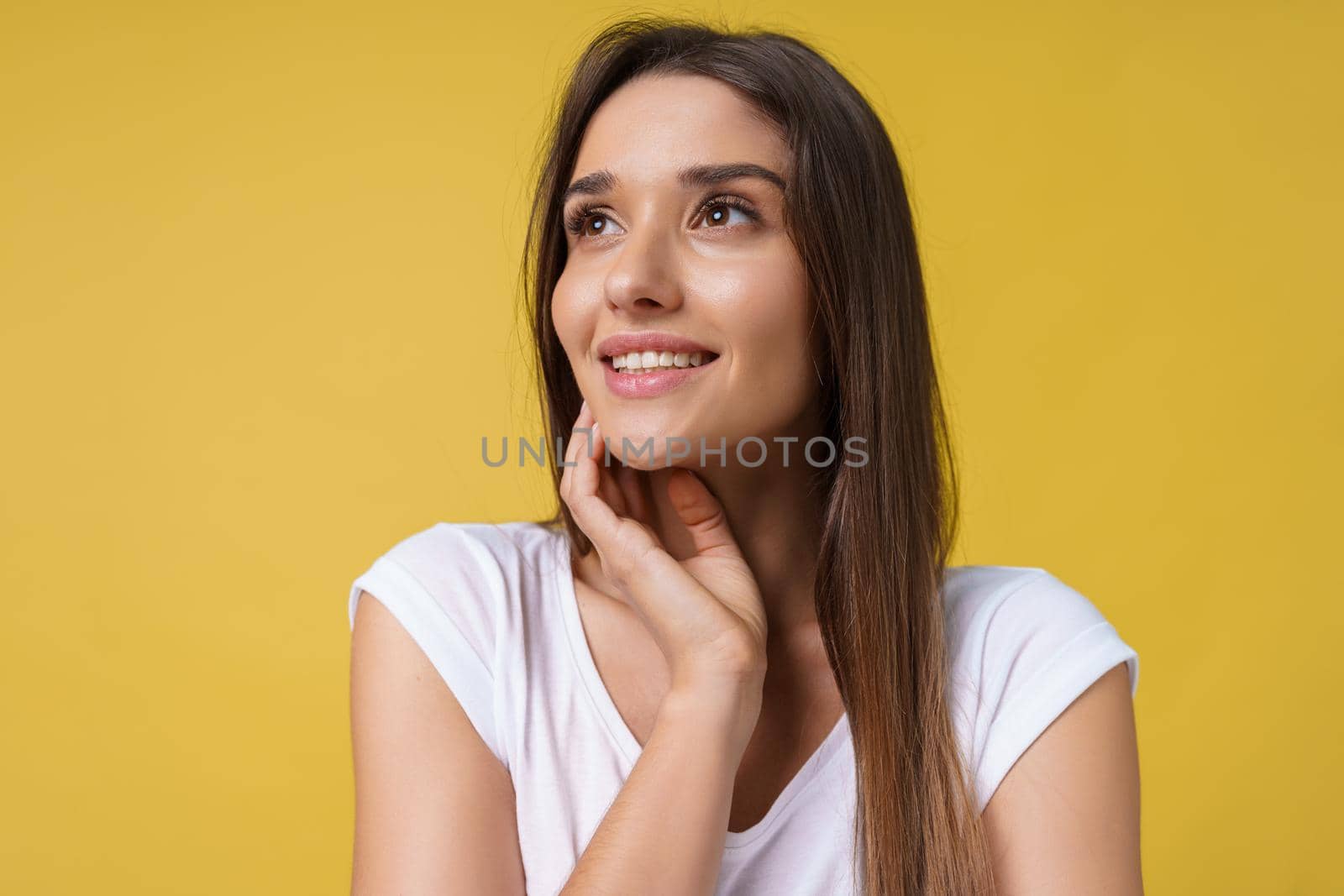 Happy cheerful young woman with joyful and charming smile isolated over yellow background. by Benzoix