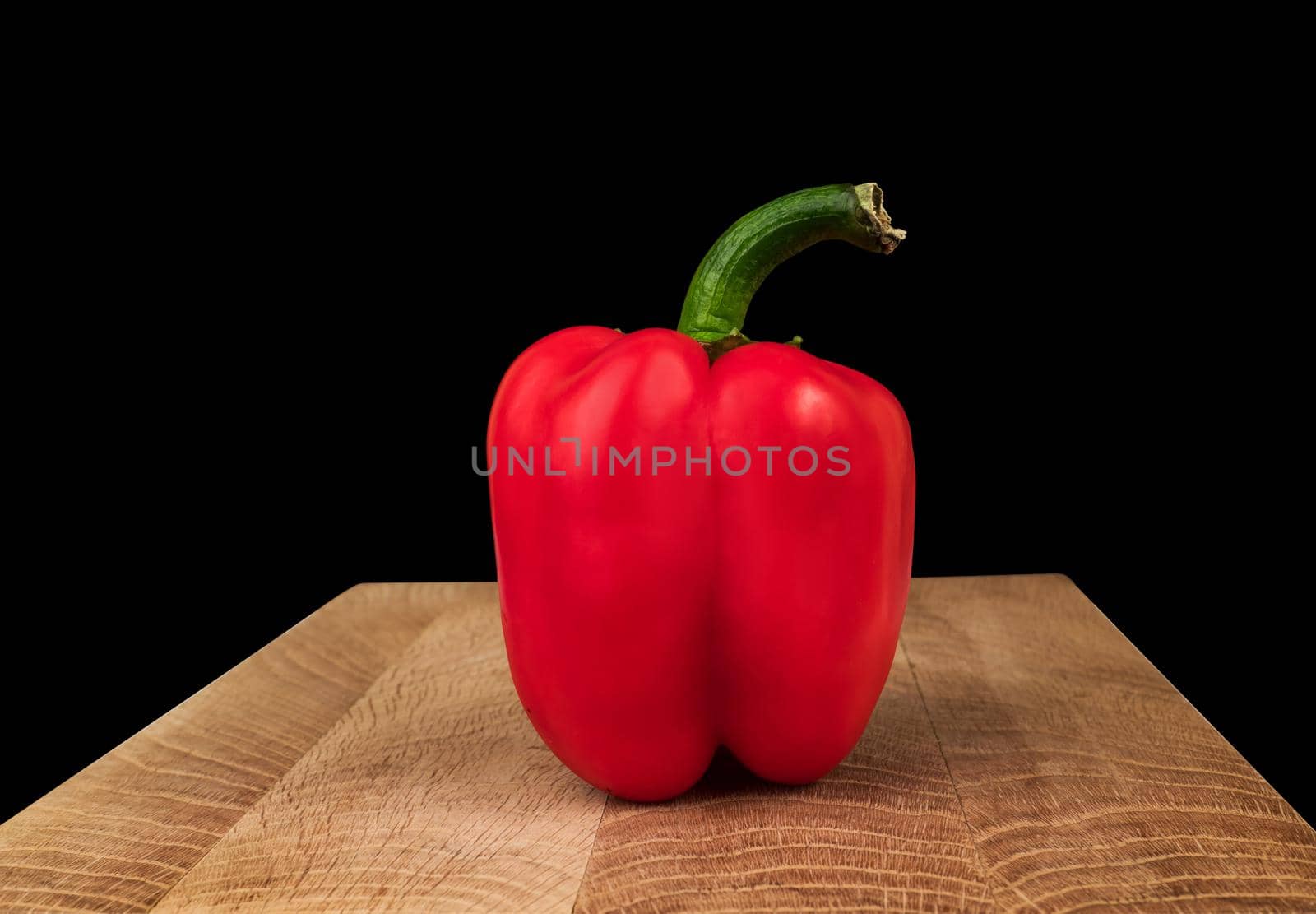 Ripe bell peppers, red, on a wooden board on a black background, place for text, template for a banner