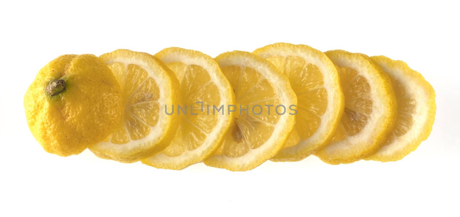 Lemon sliced in wedges and laid out in a row on a white background