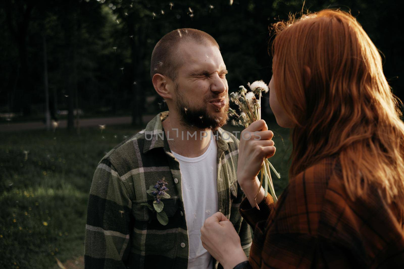 red girl blows a dandelion on her boyfriend