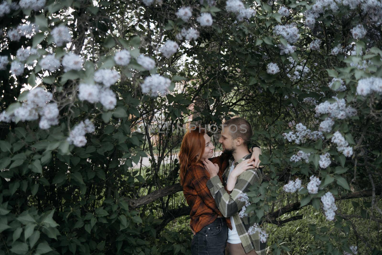 lovers embrace standing under lilacs by Symonenko