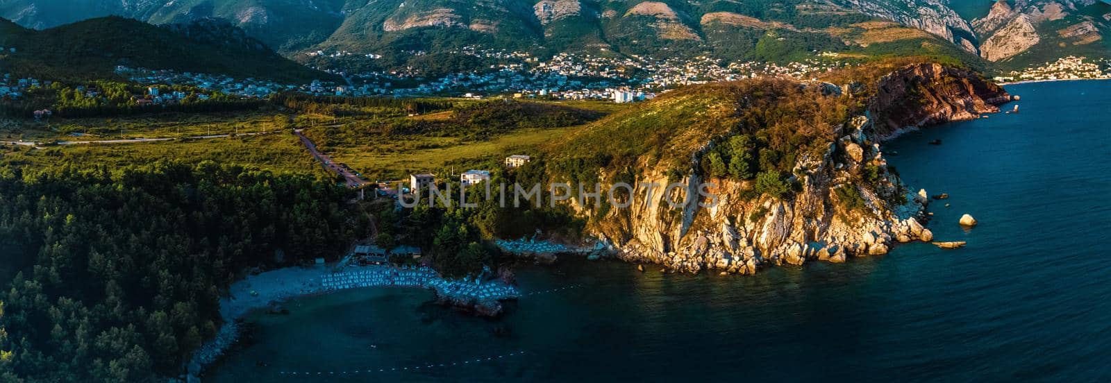 Aerial top evening view drone above Adriatic sea Montenegro. panoramic sunny marine mountain sunset. summer nature wallpaper. dark calm water rock. mountains coast seaside. Amazing outdoors view town