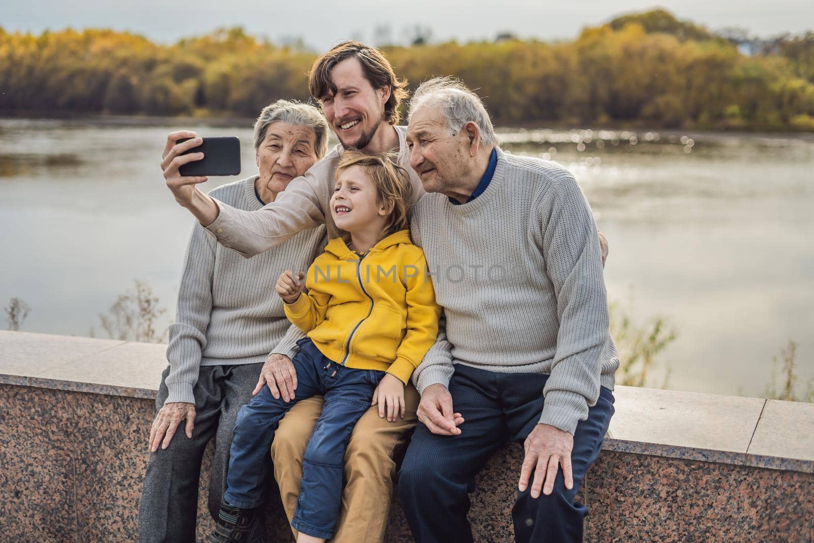 Senior couple with grandson and great-grandson take a selfie in the autumn park. Great-grandmother, great-grandfather and great-grandson.