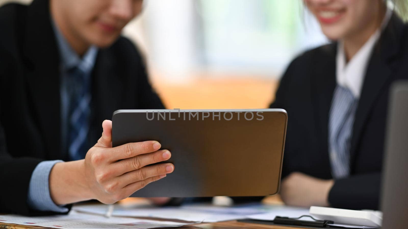 Professional businesspeople using digital tablet, checking, analyzing financial reports together at office.