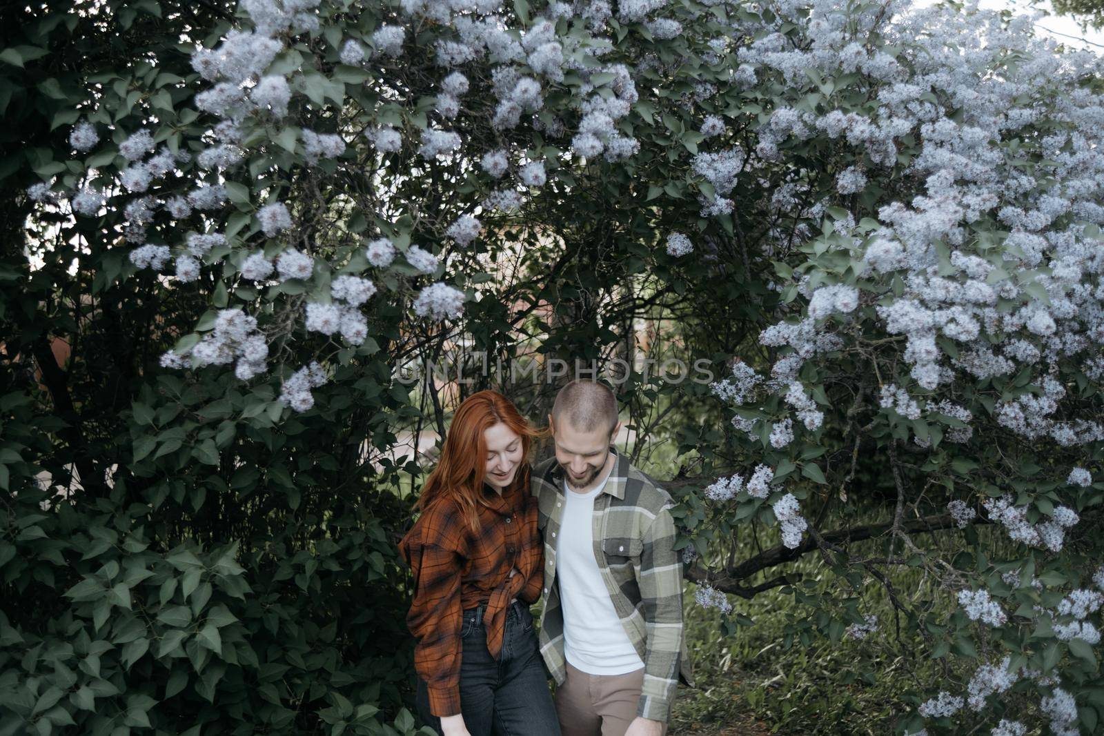 lovers embrace standing under lilacs by Symonenko