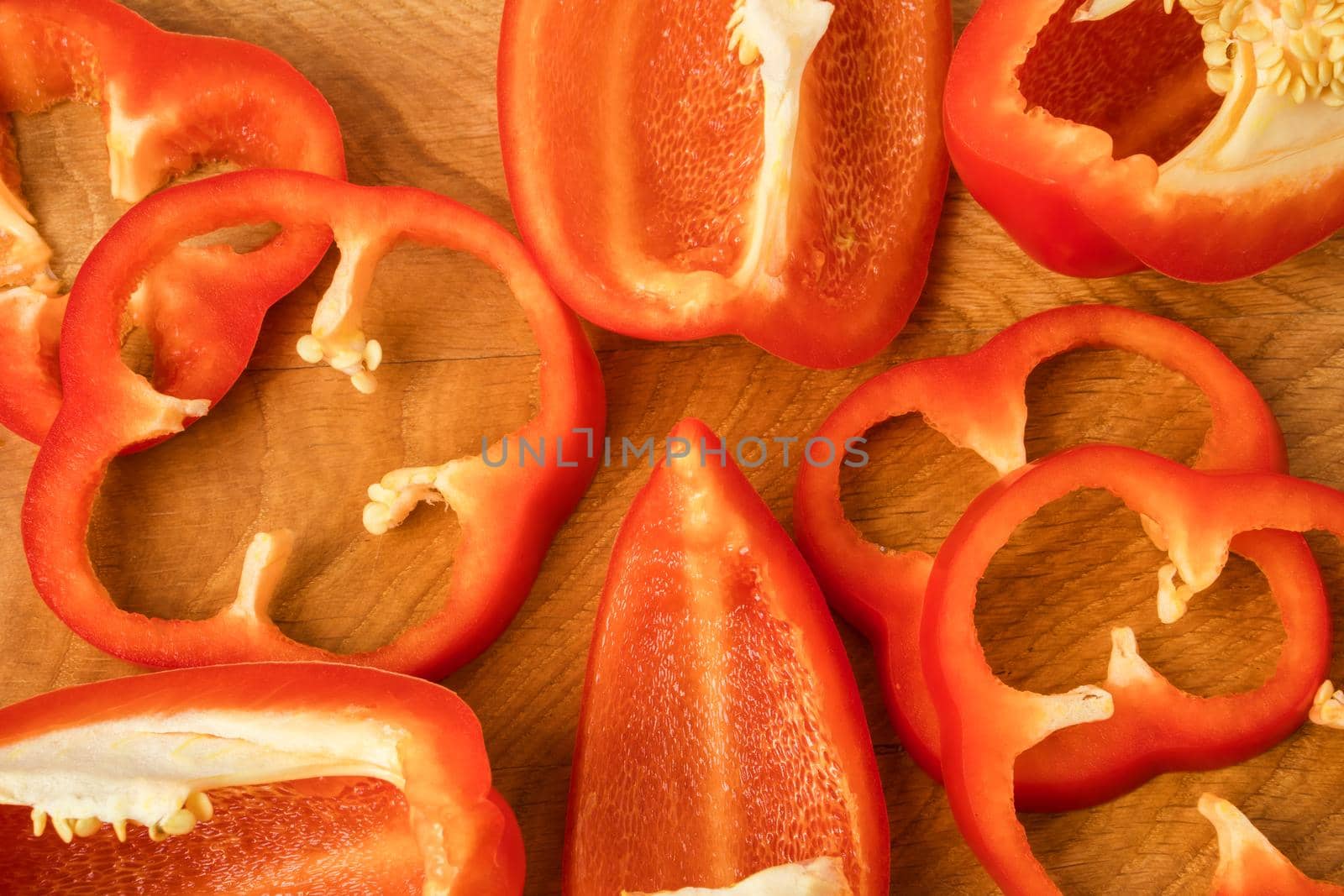 Sliced pieces, parts, lobes of sweet pepper, red, on a wooden board