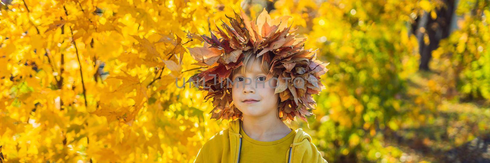 Portrait of little smiling child with wreath of leaves on head background of sunny autumn park BANNER, LONG FORMAT by galitskaya