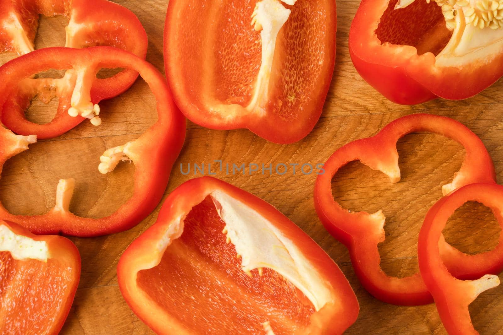 Sliced pieces, parts, lobes of sweet pepper, red, on a wooden board