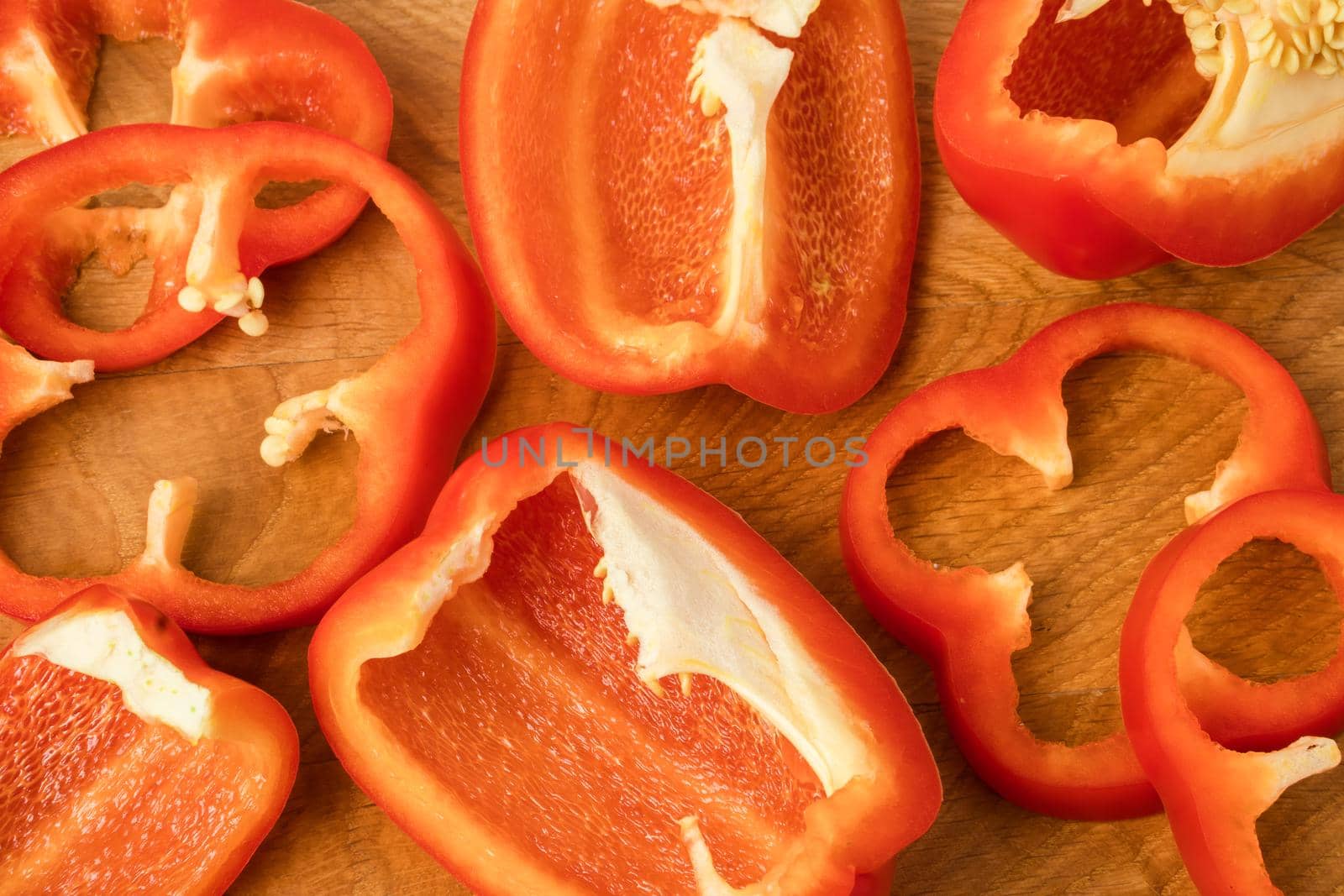 Sliced pieces, parts, lobes of sweet pepper, red, on a wooden board