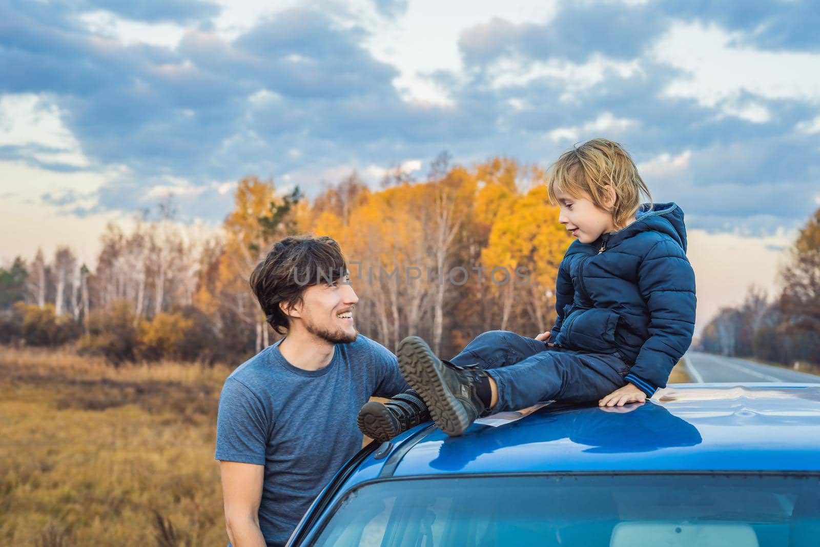 Dad and son are resting on the side of the road on a road trip. Road trip with children concept by galitskaya