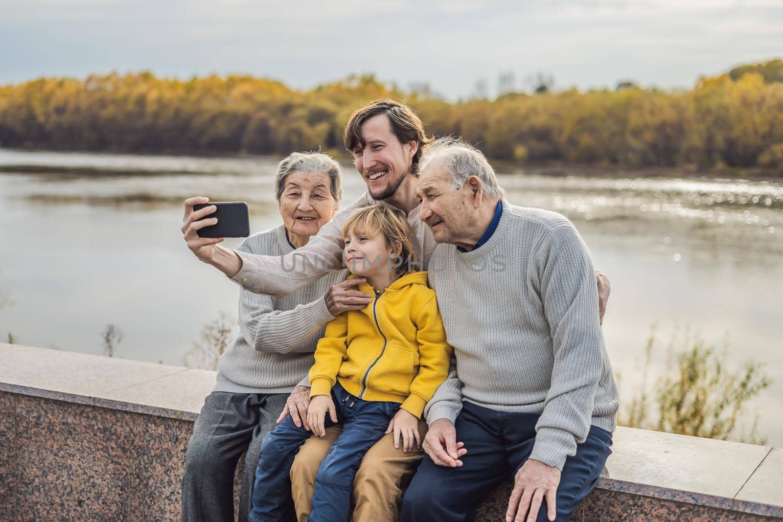 Senior couple with grandson and great-grandson take a selfie in the autumn park. Great-grandmother, great-grandfather and great-grandson.