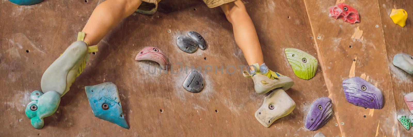 little boy climbing a rock wall in special boots. indoor BANNER, LONG FORMAT by galitskaya