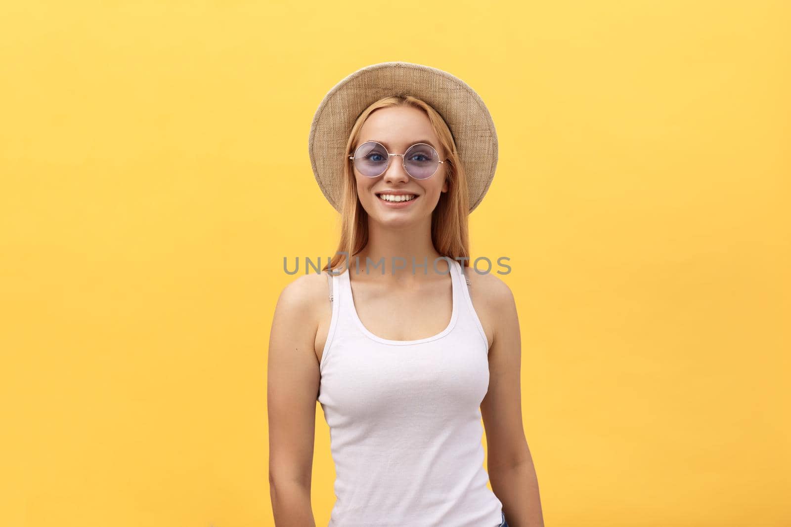Happy stylish modern woman with modern shaped sunglasses laughing looking at you camera isolated on yellow background. Happiness concept by Benzoix