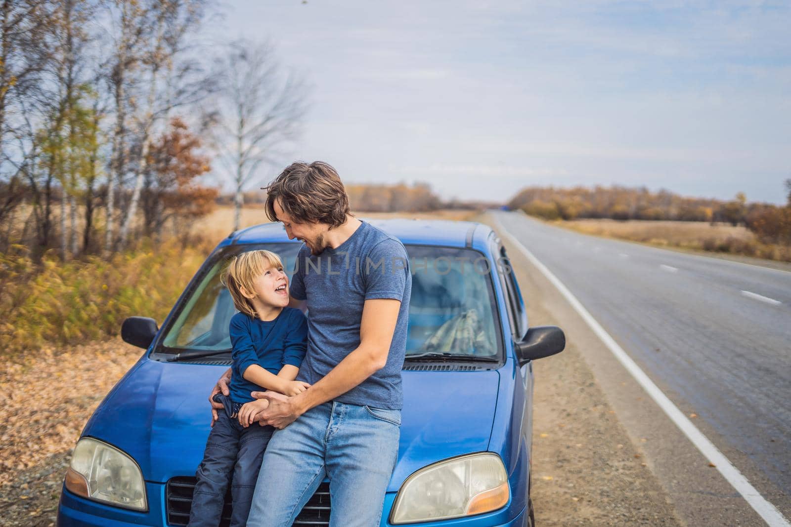 Dad and son are resting on the side of the road on a road trip. Road trip with children concept by galitskaya