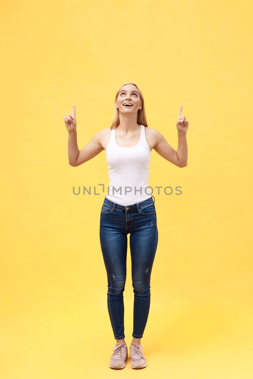 Full length portrait of successful young woman celebrating her victory. Isolated on yellow background.