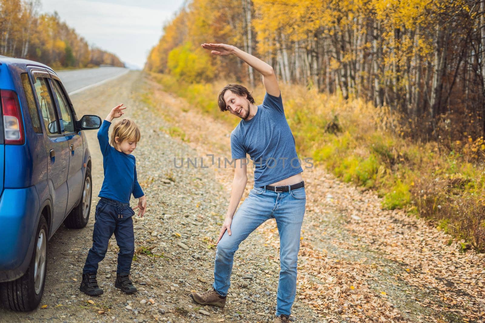 Dad and son are resting on the side of the road on a road trip. Road trip with children concept.