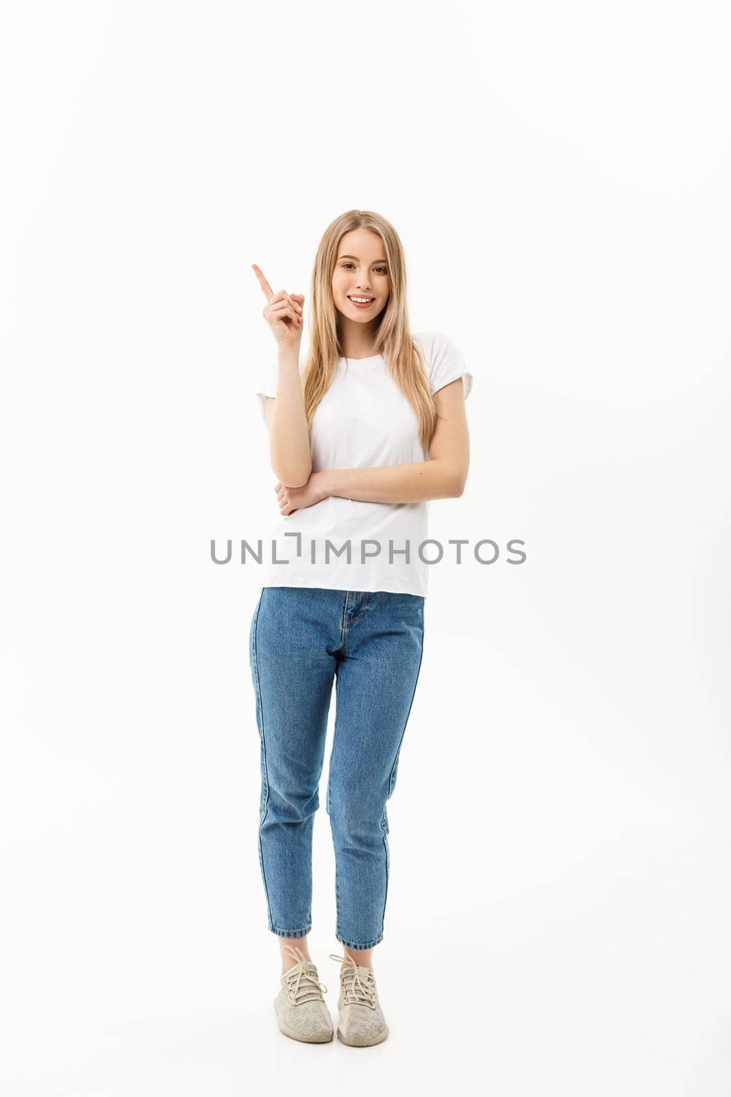 Young attractive happy woman in casual cloth pointing at white copy space background.