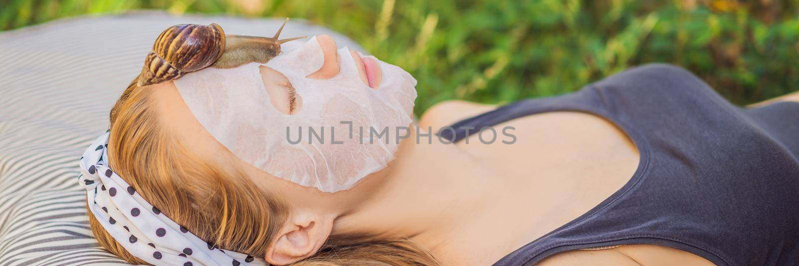 Young woman makes a face mask with snail mucus. Snail crawling on a face mask. BANNER, LONG FORMAT