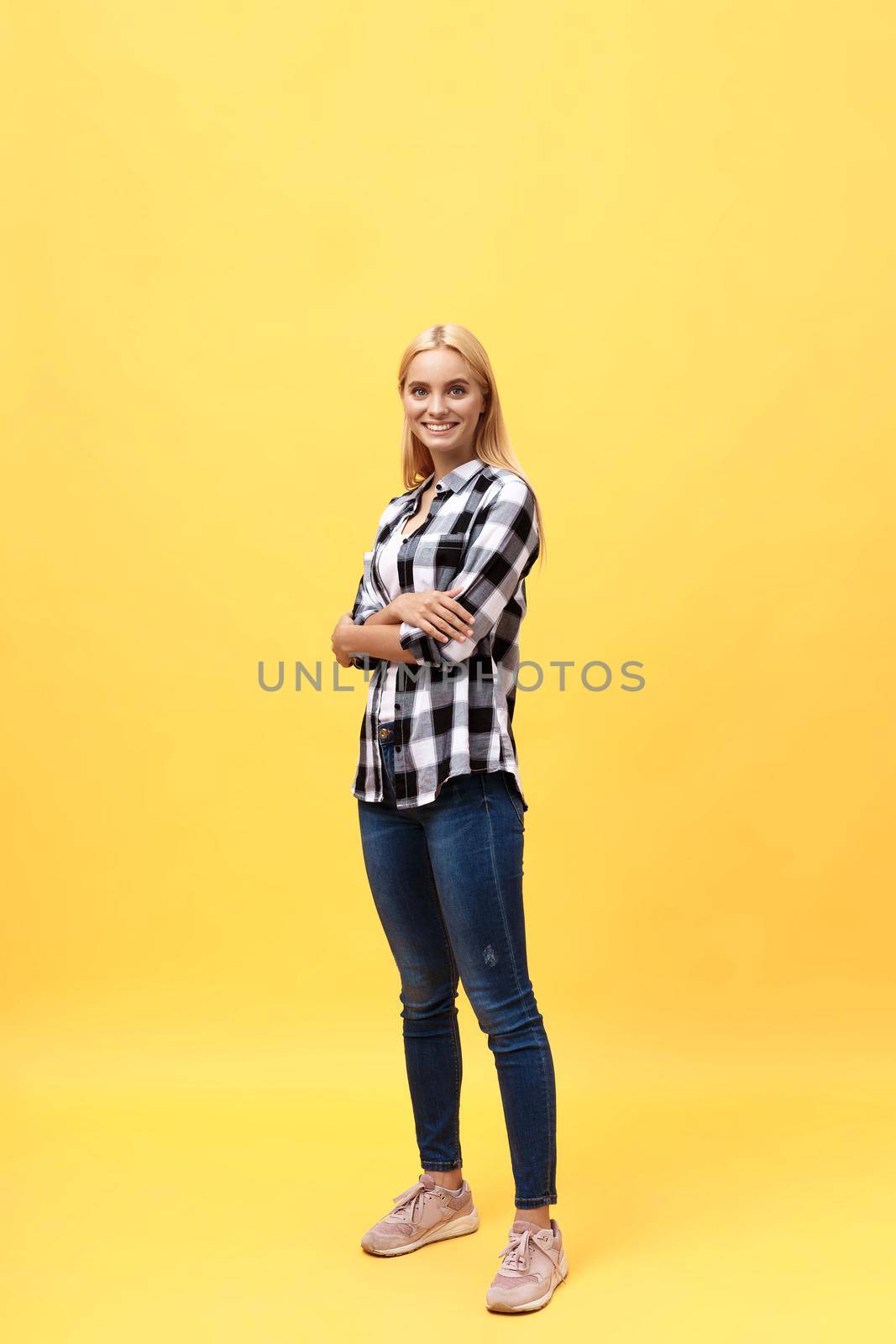 Full length laughing model in studio. looking at camera. isolated yellow background.