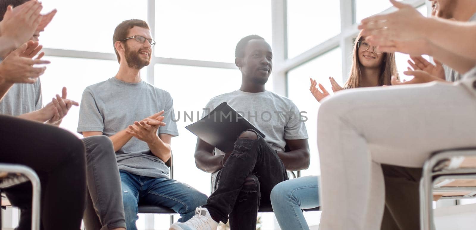 smiling speaker sitting in a circle of young people by asdf