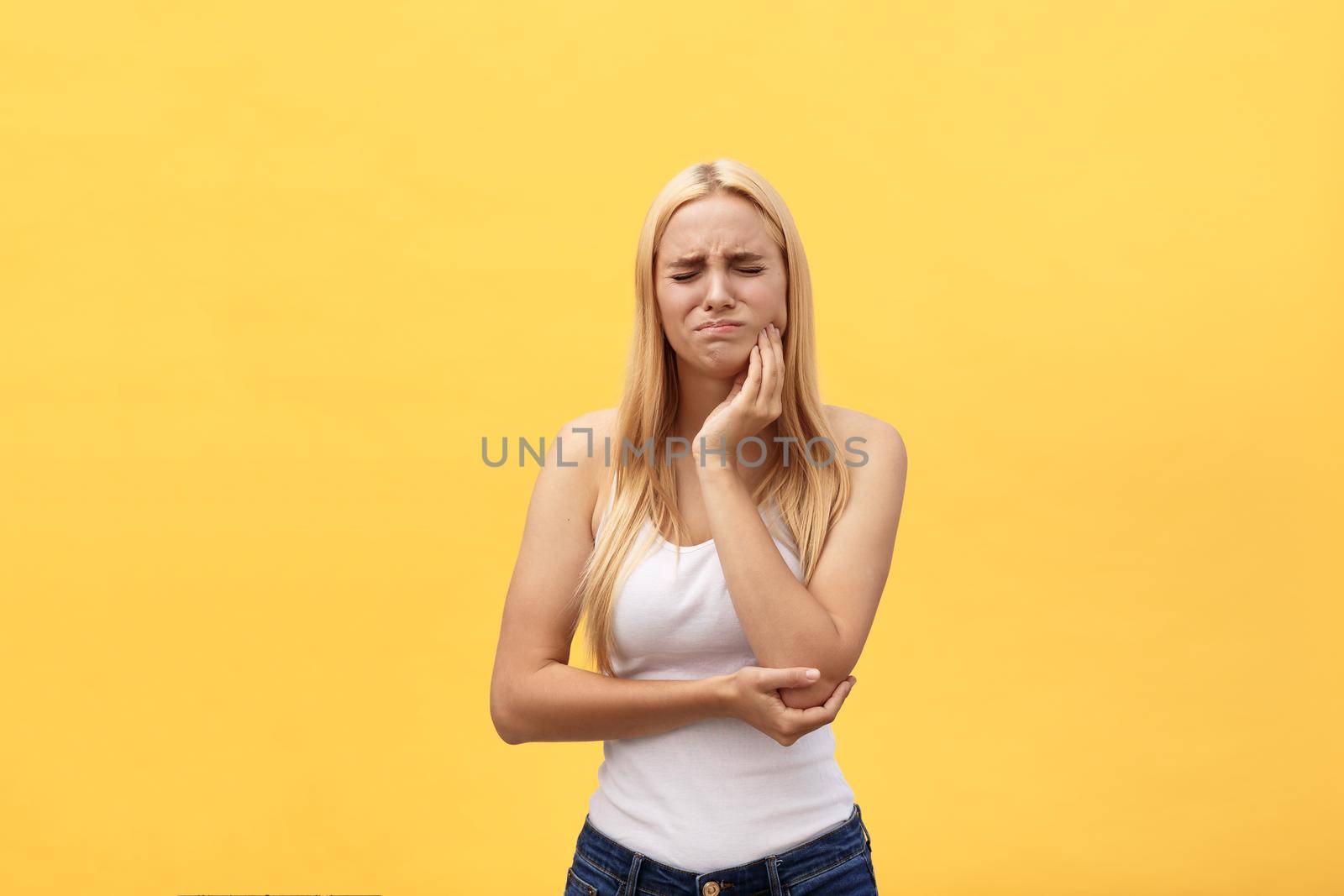 Beautiful young woman suffering from toothache on yellow background by Benzoix