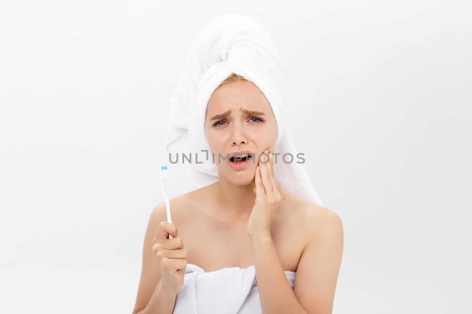 Young caucasian woman with toothache while brushing her teeth.