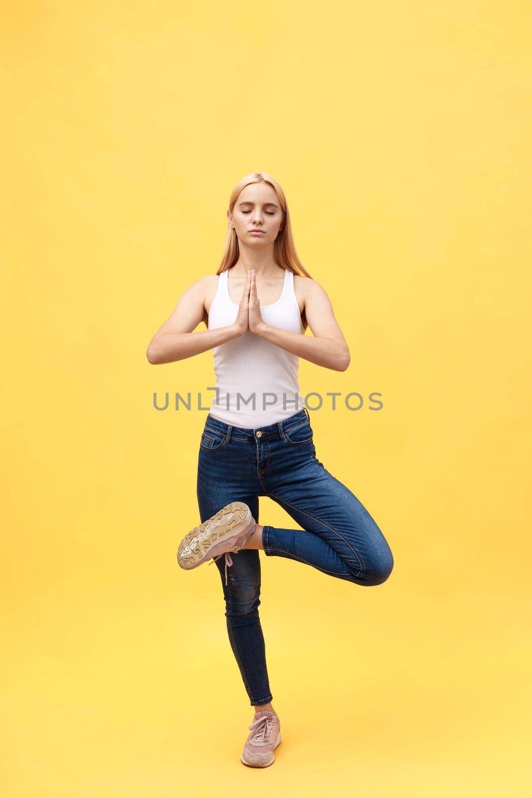 Sporty attractive young woman in white sportswear doing exercise for spine, Vrikshasana pose, hands above the head in Anjali mudra, part of large photo series, isolated, full length