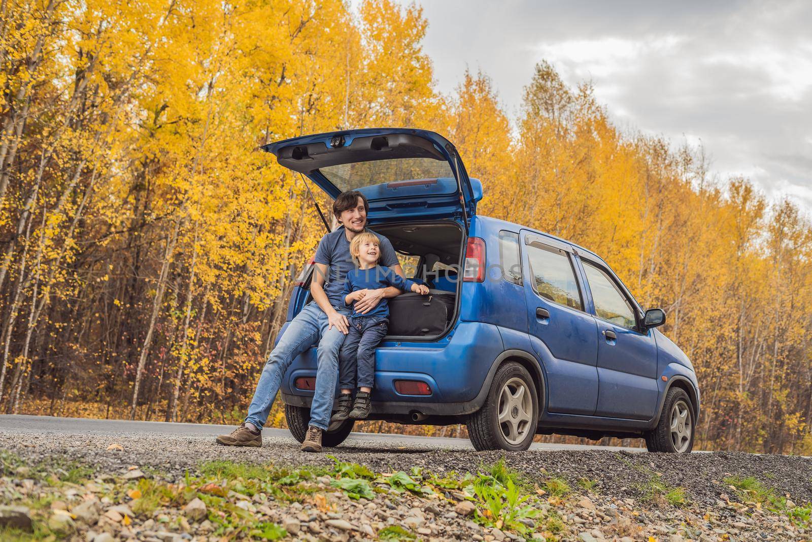 Dad and son are resting on the side of the road on a road trip. Road trip with children concept.