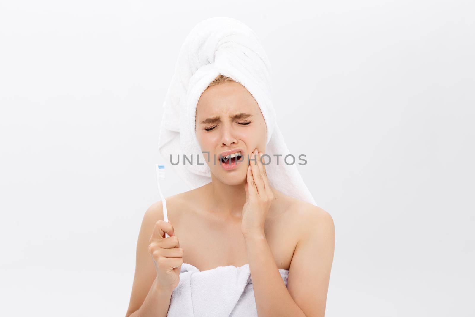 Young caucasian woman with toothache while brushing her teeth by Benzoix
