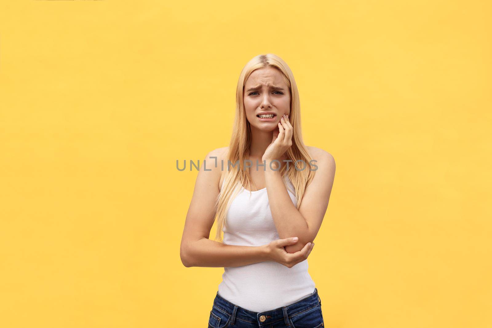 Beautiful young woman suffering from toothache on yellow background.