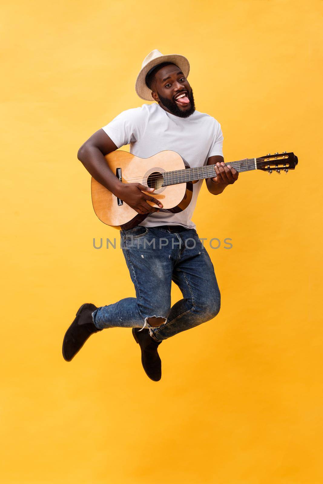 Full-length photo of excited artistic man playing his guitar. Isolated on yellow background