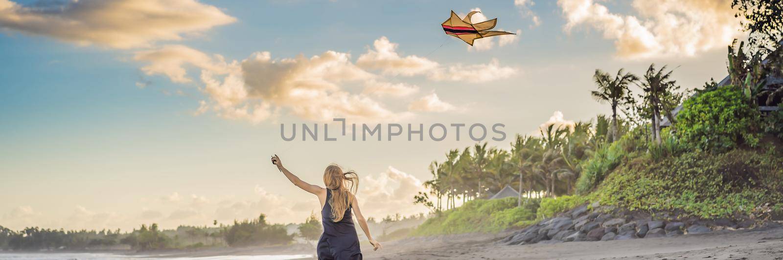 A young woman launches a kite on the beach. Dream, aspirations, future plans. BANNER, LONG FORMAT