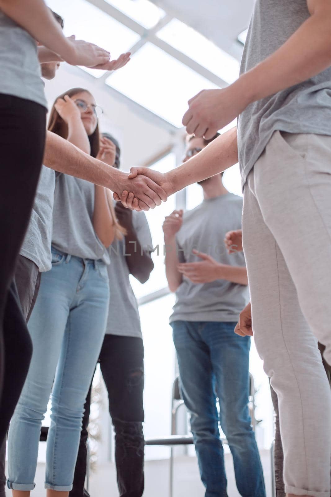 close-up. handshake of young people on the background of the applauding team