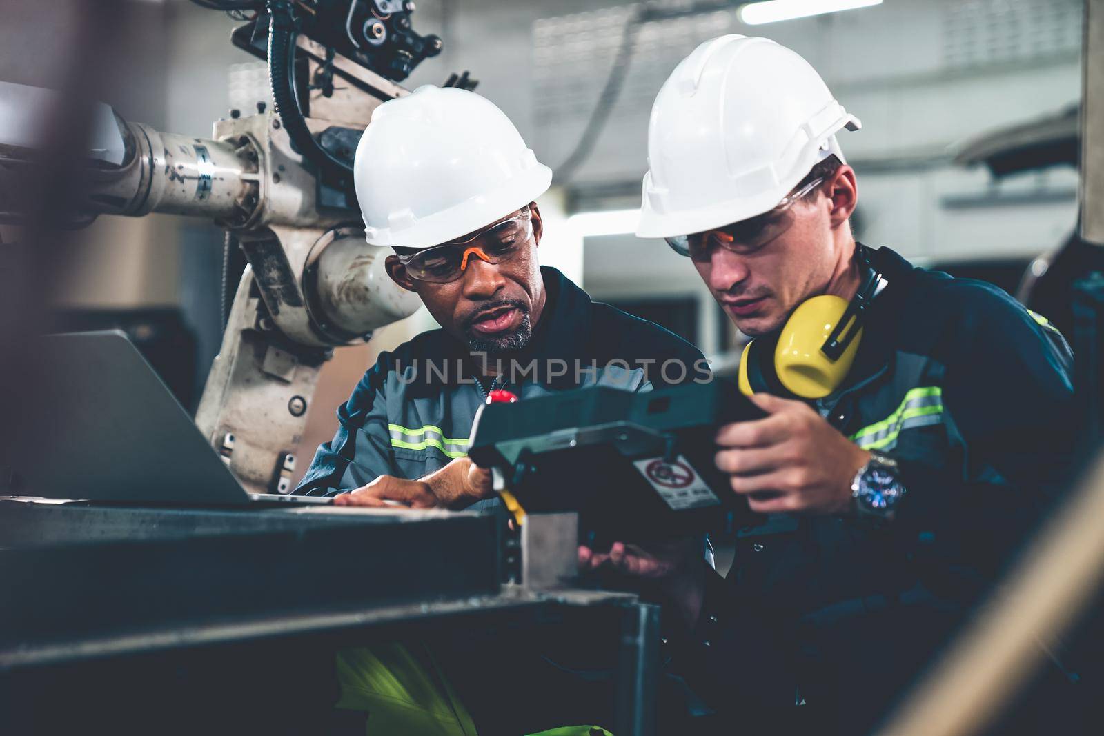 Factory workers working with adept robotic arm in a workshop . Industry robot programming software for automated manufacturing technology .