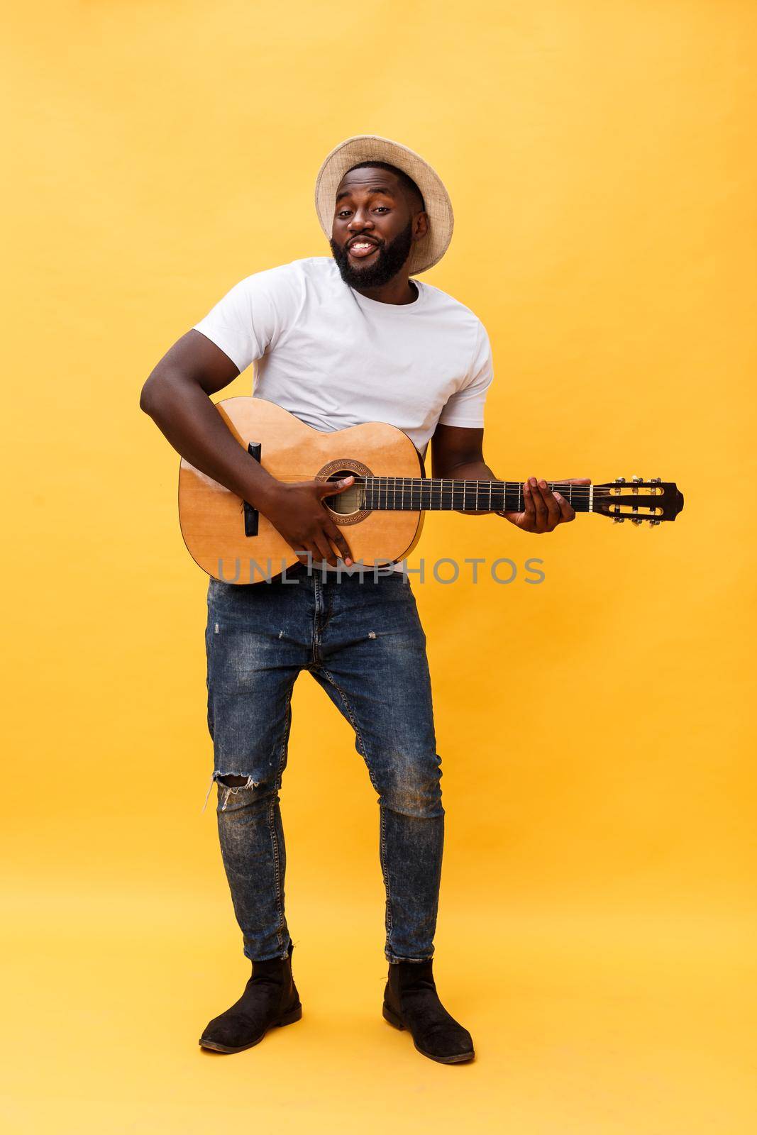 Full-length photo of excited artistic man playing his guitar in casual suite. Isolated on yellow background