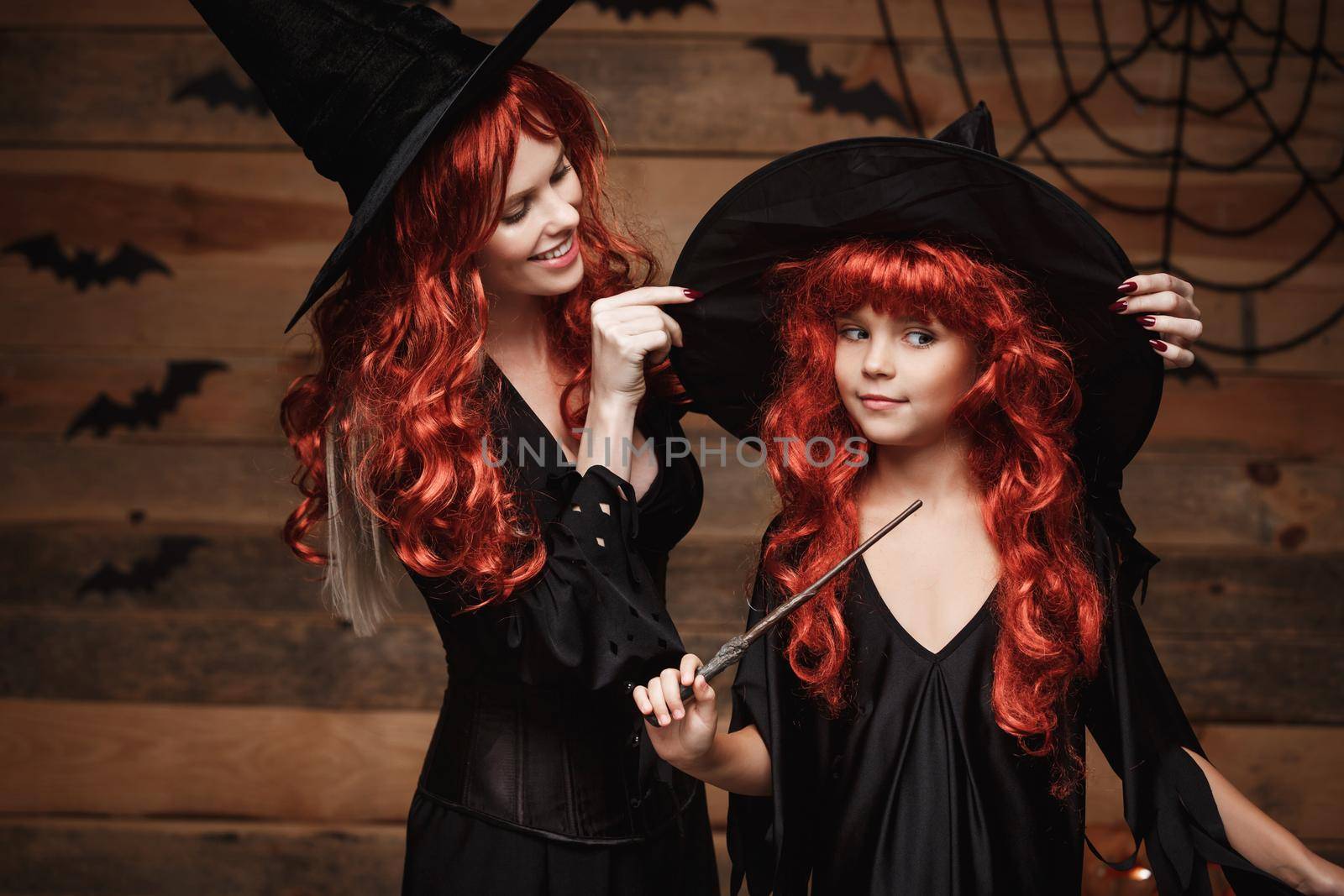 Halloween Concept - Beautiful caucasian mother dress up for her daughter in witch costumes and long curly hair ready for celebrating Halloween. by Benzoix