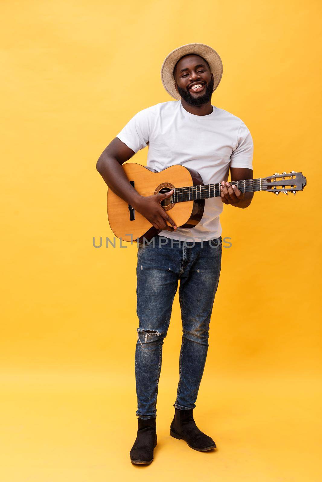 Full-length photo of excited artistic man playing his guitar. Isolated on yellow background