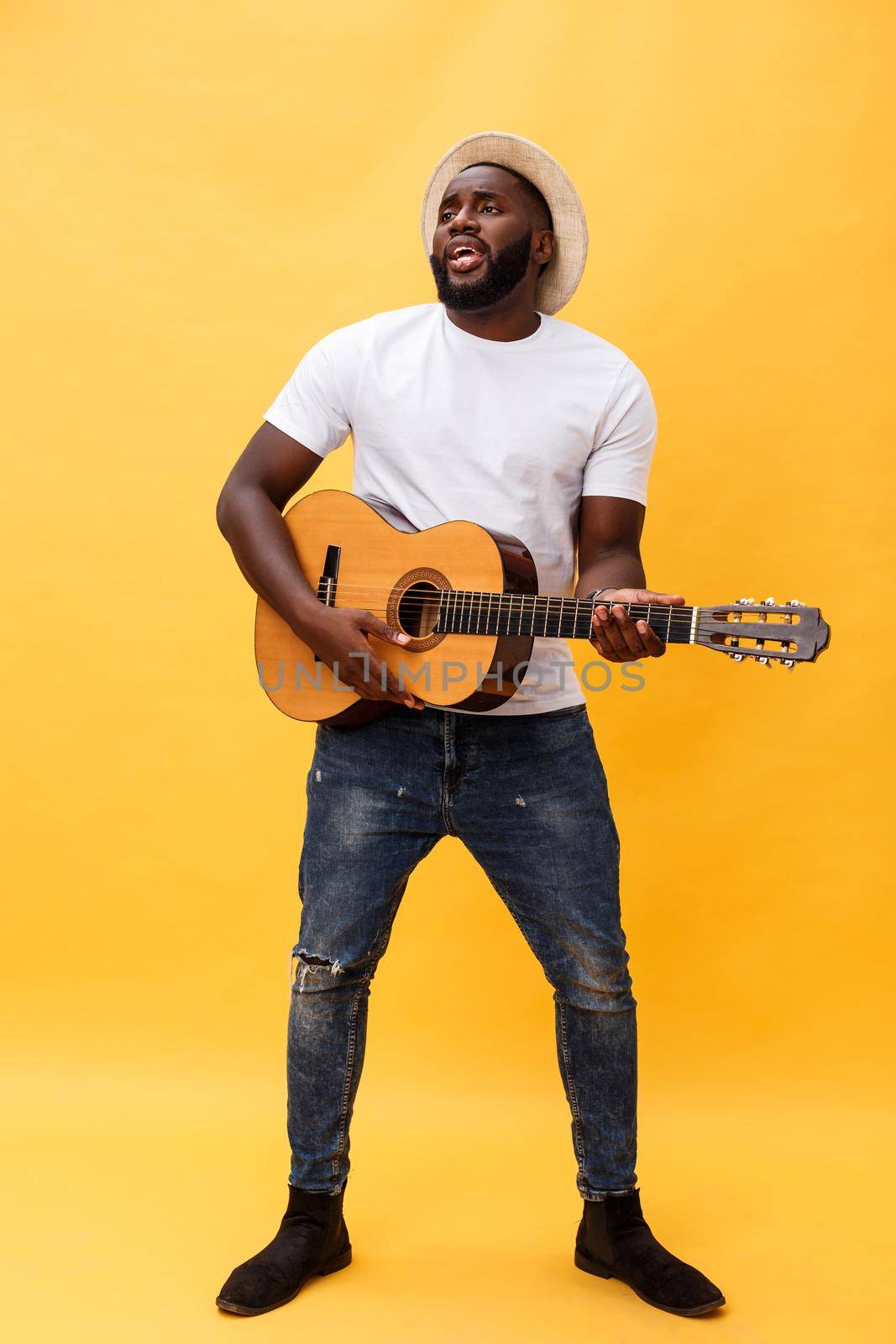 Full-length photo of excited artistic man playing his guitar in casual suite. Isolated on yellow background